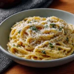 Delicious creamy garlic pasta garnished with herbs in a bowl