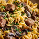 Easy beef stroganoff served in a bowl with noodles and garnished with parsley.
