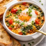 Baked feta eggs with tomatoes and spinach in a vibrant dish