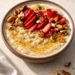 Bowl of creamy custard oatmeal topped with fresh fruits and nuts