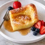 Delicious German pancakes served with syrup and fruit on a plate