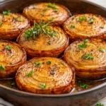 Bowl of marinated roasted onions garnished with herbs.