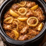 Slow cooker pork loin served with sauerkraut and apples on a rustic table