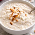 Delicious bowl of coconut cream oats topped with fresh fruits and nuts