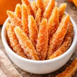 Homemade candied orange peels on a rustic wooden table.