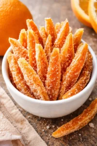 Homemade candied orange peels on a rustic wooden table.