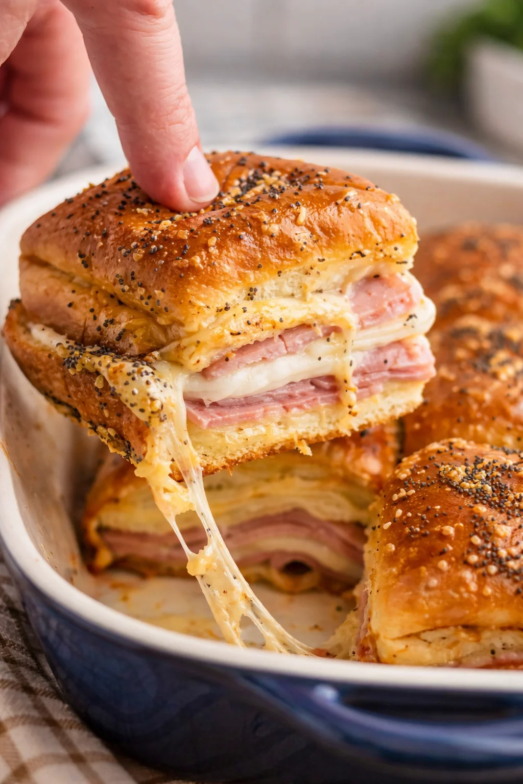 Ham and cheese sliders on a platter, topped with herbs and seasonings.