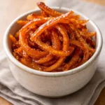 Homemade candied orange peels in a bowl, a sweet and tangy treat.