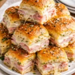 Hot ham and cheese sliders served on a platter with garnish.