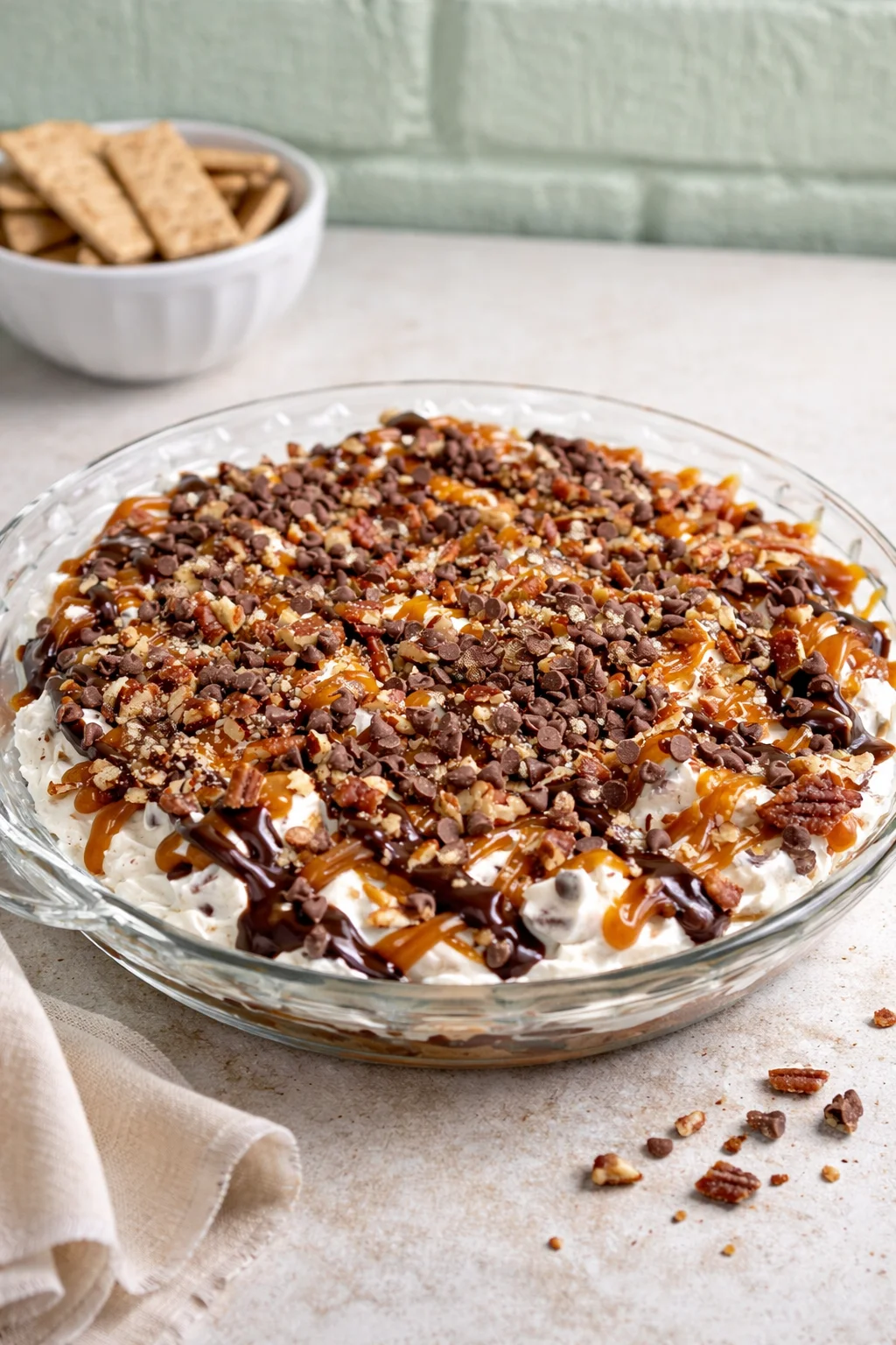 Turtle cheesecake dip served in a bowl with chocolate and caramel toppings.