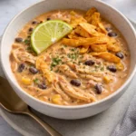White chicken chili recipe with cream cheese in a bowl garnished with herbs