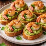 Garlic shrimp crostini topped with creamy avocado on toasted bread