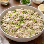 A healthy tuna salad bowl topped with fresh vegetables and herbs