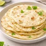 Homemade sourdough tortillas on a wooden surface with ingredients.