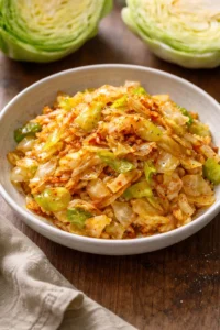 Dish of paprika sautéed cabbage served on a plate with fresh herbs