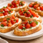 Whipped feta tomato crostini topped with fresh tomatoes on toasted bread