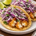 Plate of crispy fish tacos topped with fresh ingredients