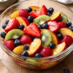 Fruit salad topped with honey lime dressing in a vibrant bowl.
