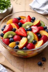 Fruit salad topped with honey lime dressing in a vibrant bowl.