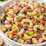 Bowl of colorful Mexican Macaroni Salad garnished with cilantro and lime.