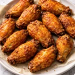 Crispy air fryer chicken wings garnished with herbs on a plate.
