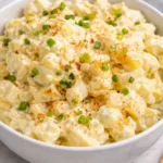 Bowl of creamy potato salad with herbs and vegetables