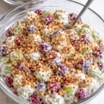 A vibrant grape salad with mixed fruits and a creamy dressing on a white plate.