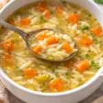 Bowl of delicious orzo soup filled with vegetables and herbs